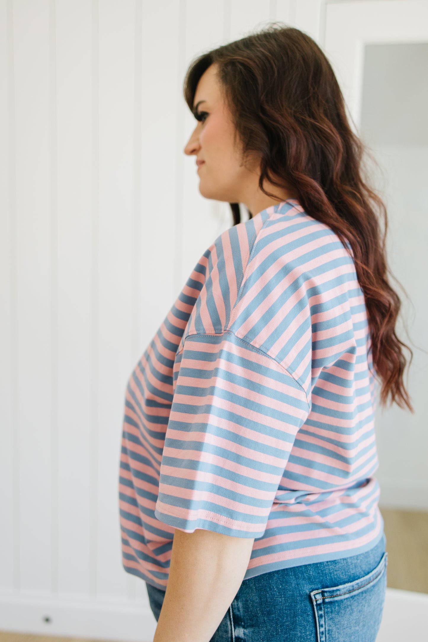Woman wearing a pink and blue striped shirt with a white background