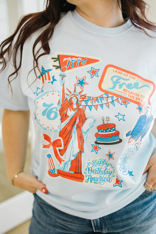 Person wearing a t-shirt with a colorful graphic design featuring the Statue of Liberty and text.