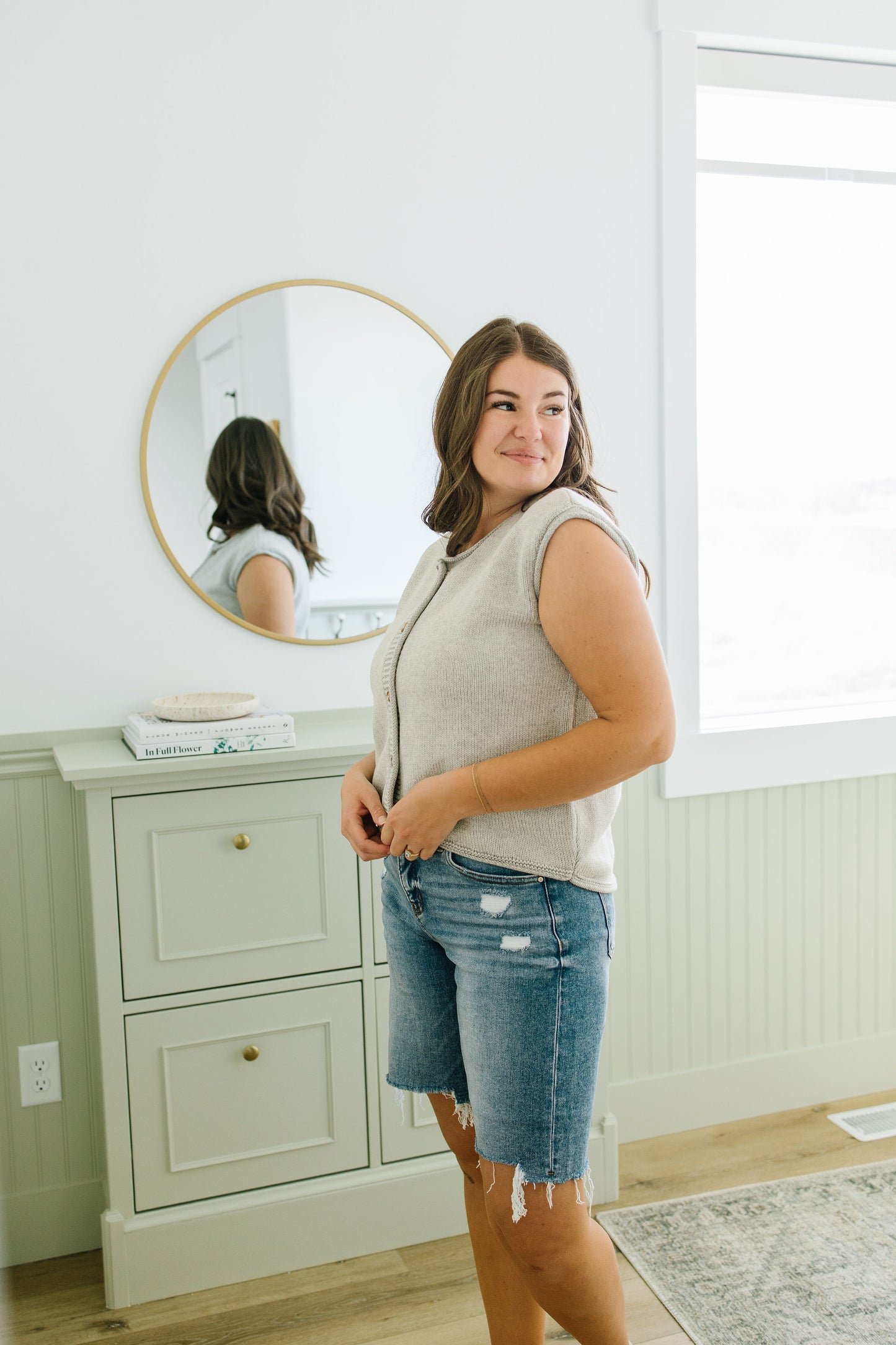 Woman standing in a room with a mirror and window