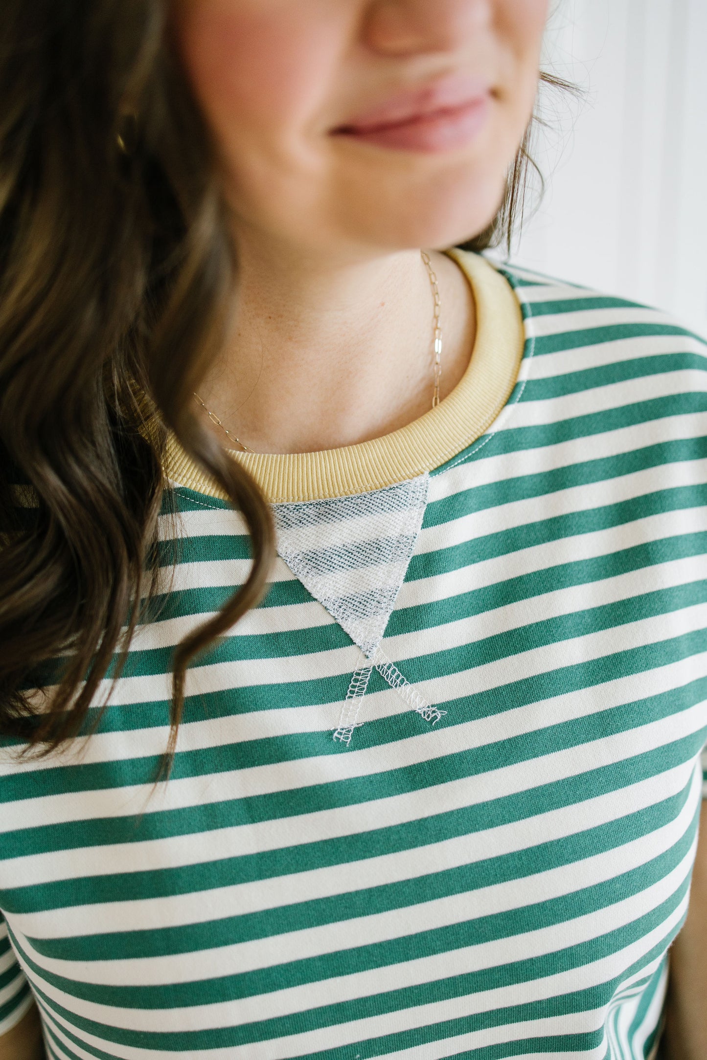 Person wearing a green and white striped shirt with a yellow collar.