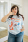 Woman wearing a patriotic graphic t-shirt in front of a mirror