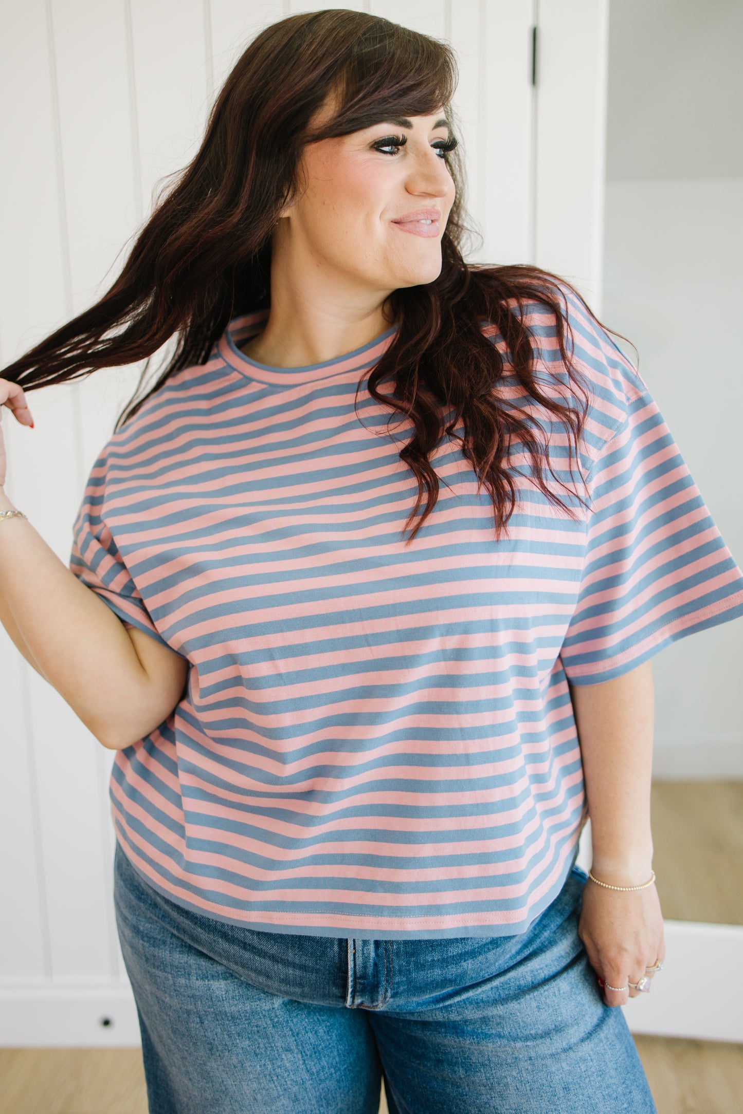 Woman wearing a striped shirt and jeans indoors.