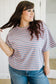 Woman wearing a striped shirt and jeans indoors.