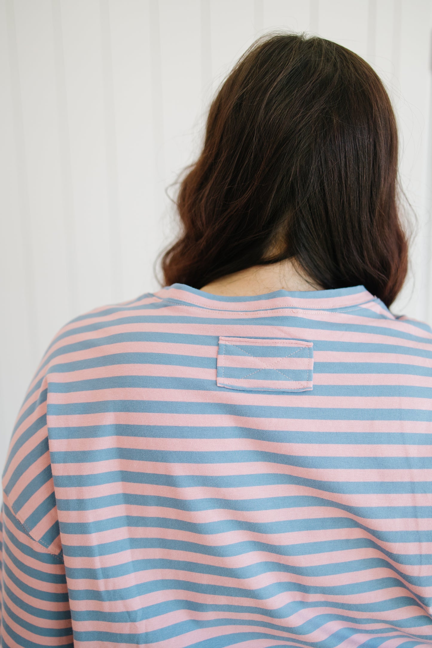 Person wearing a pink and blue striped shirt with a white background