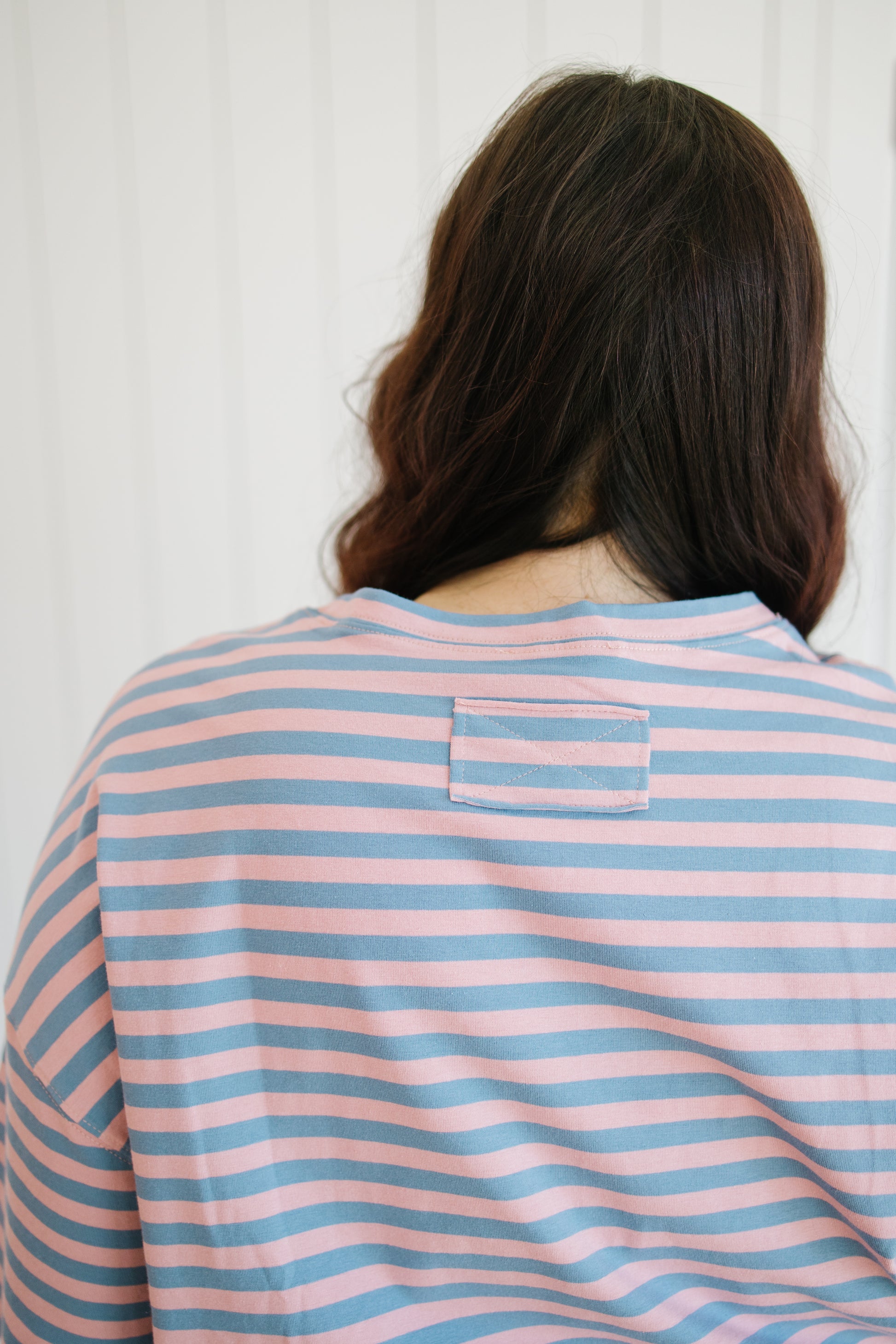 Person wearing a pink and blue striped shirt with a white background