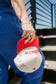 Person holding a red and white cap with 'MOTHER' printed on it, wearing a blue outfit.