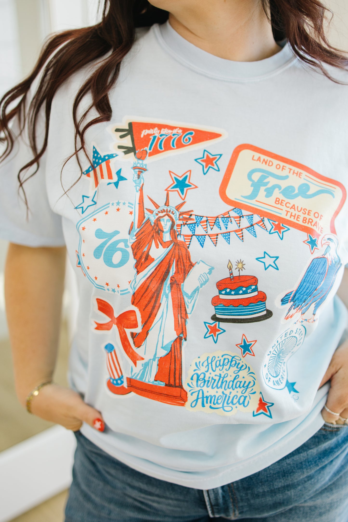 Person wearing a t-shirt with a colorful graphic design featuring the Statue of Liberty and text.