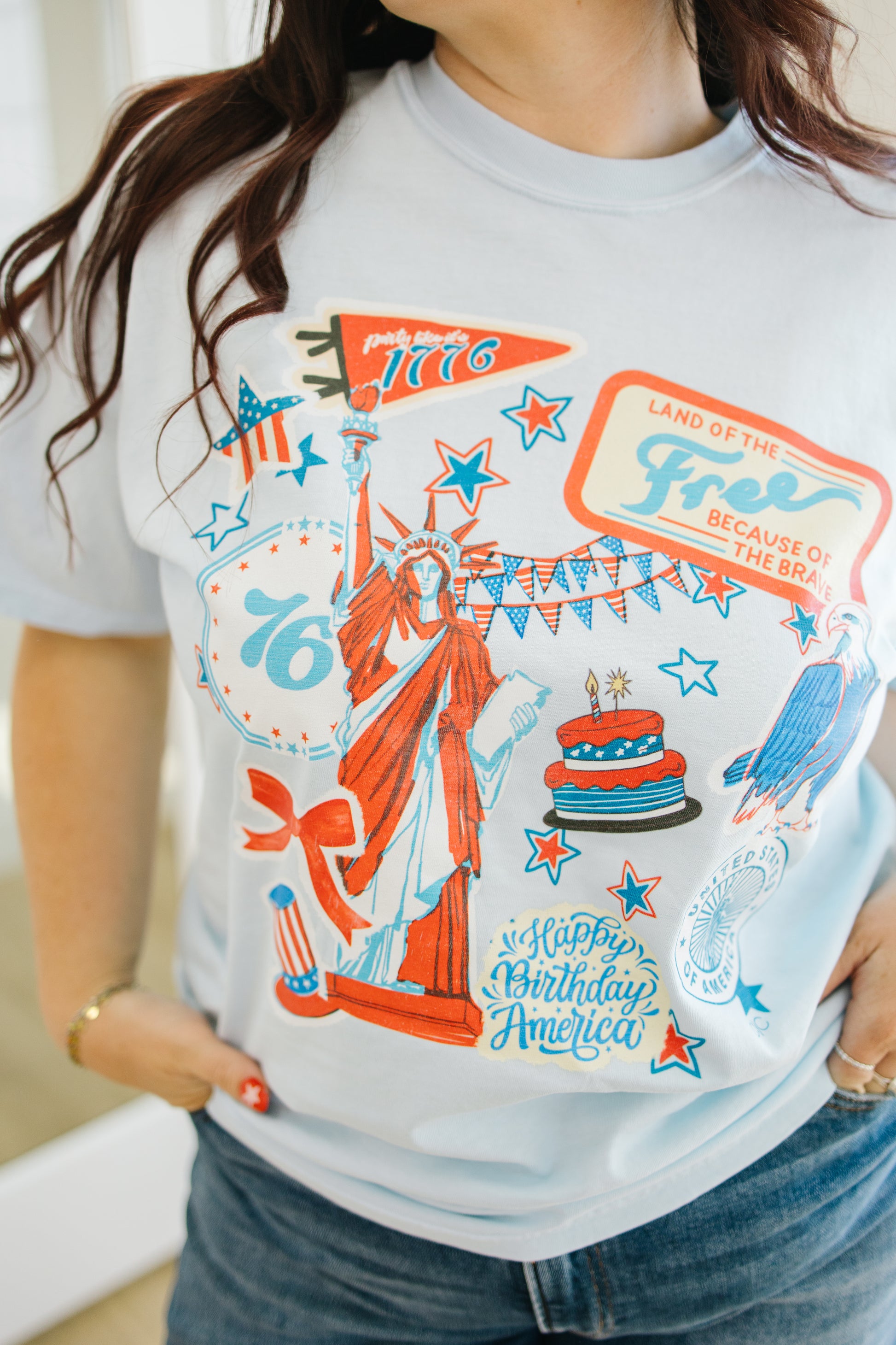 Person wearing a t-shirt with a colorful graphic design featuring the Statue of Liberty and text.