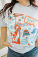 Person wearing a t-shirt with a colorful graphic design featuring the Statue of Liberty and text.