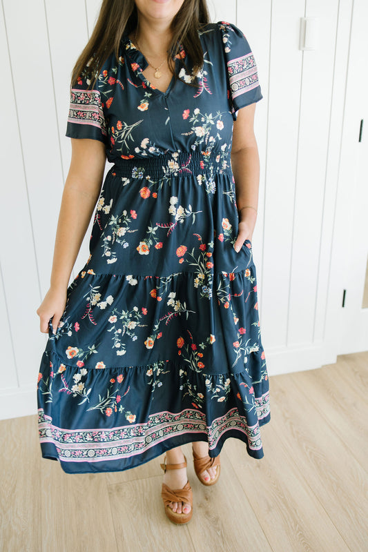 Woman wearing a navy floral dress with a white background