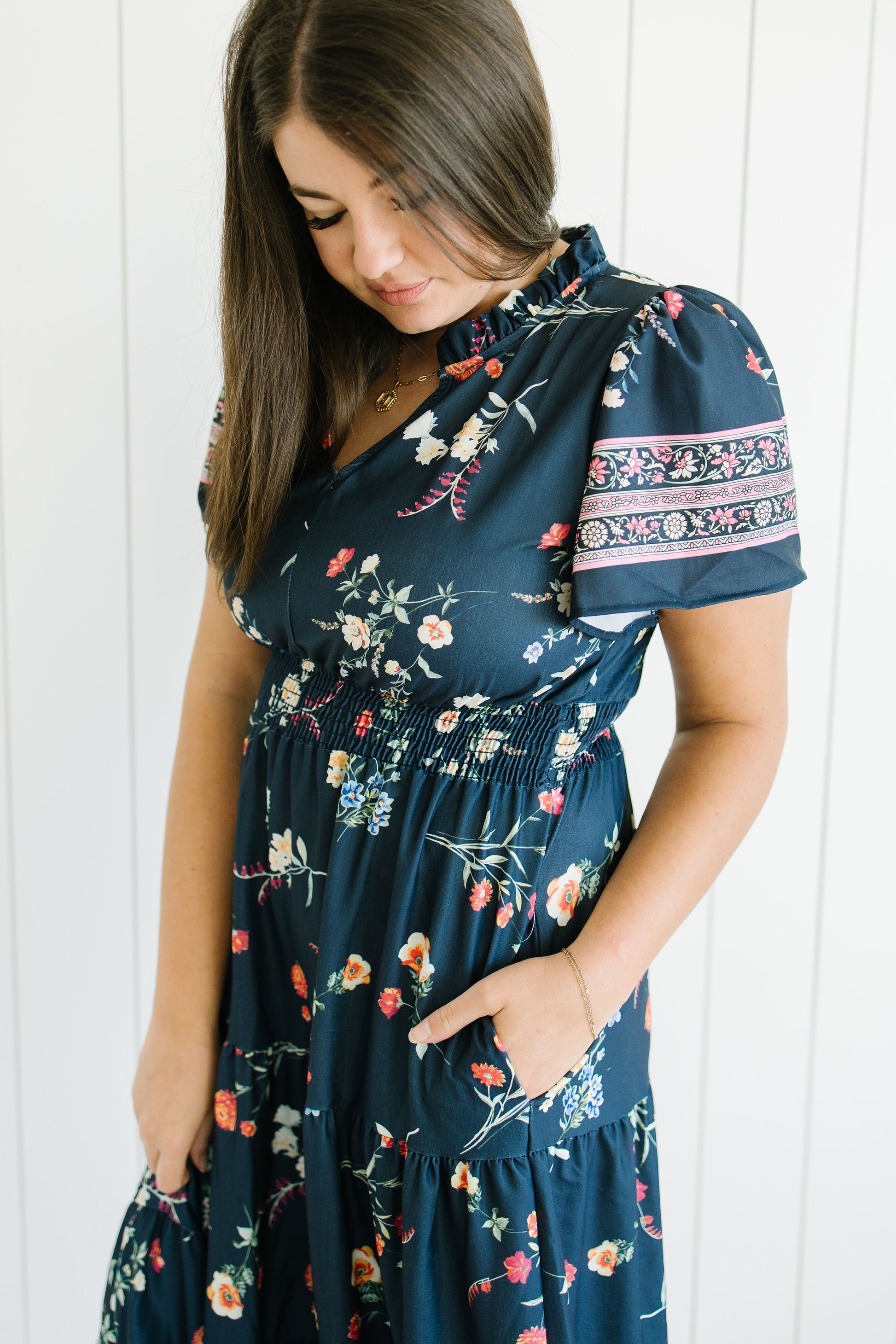 Woman wearing a navy floral dress against a white background