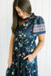 Woman wearing a navy floral dress against a white background