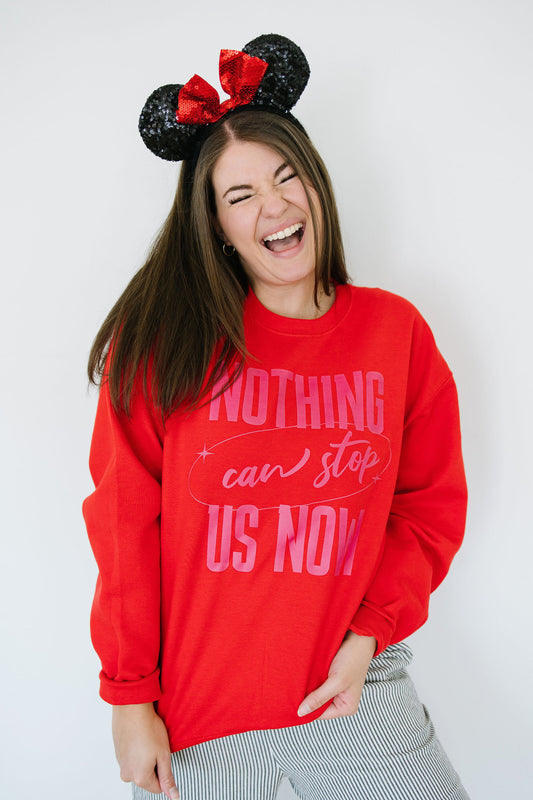 Person wearing a red sweatshirt with pink text and Minnie Mouse ears against a white background