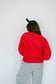 Person wearing a red sweatshirt and gray pants against a white background
