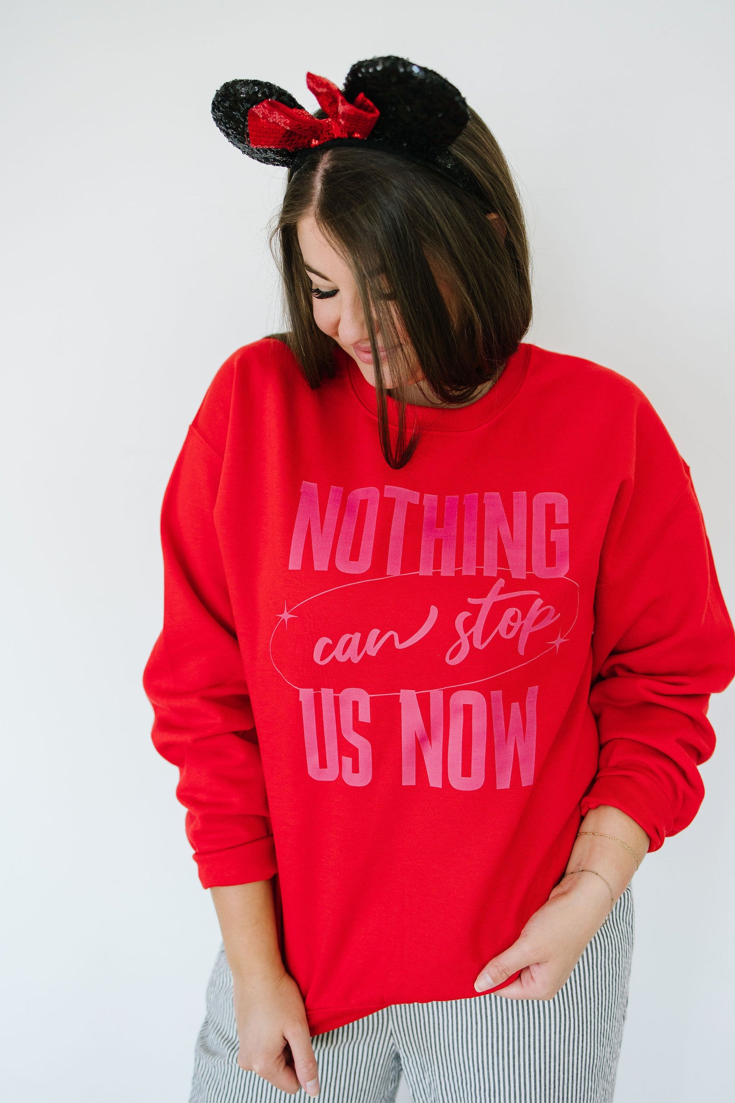 Person wearing a red sweatshirt with 'Nothing can stop us now' text and Minnie Mouse ears.