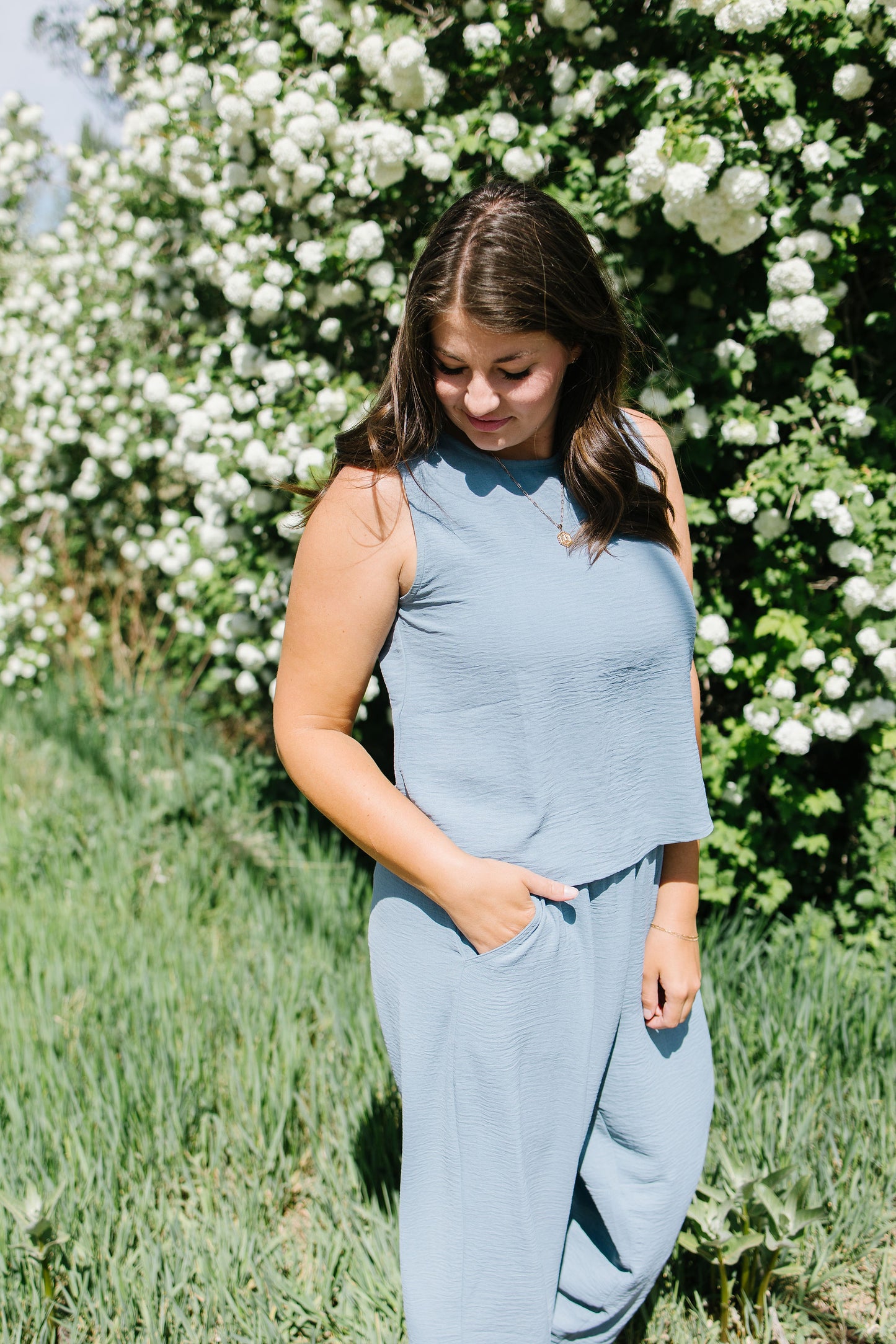 Woman in a light blue outfit standing in front of white flowers