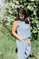 Woman in a light blue outfit standing in front of white flowers