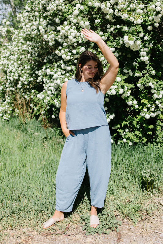 Woman in a light blue outfit standing in front of a white flower bush