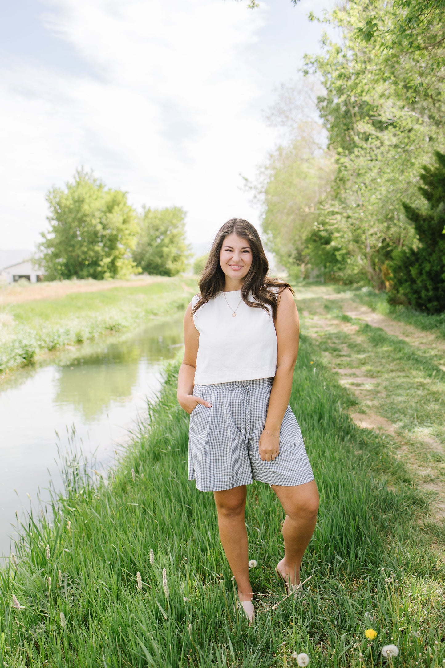 Woman standing by a pond with greenery in the background