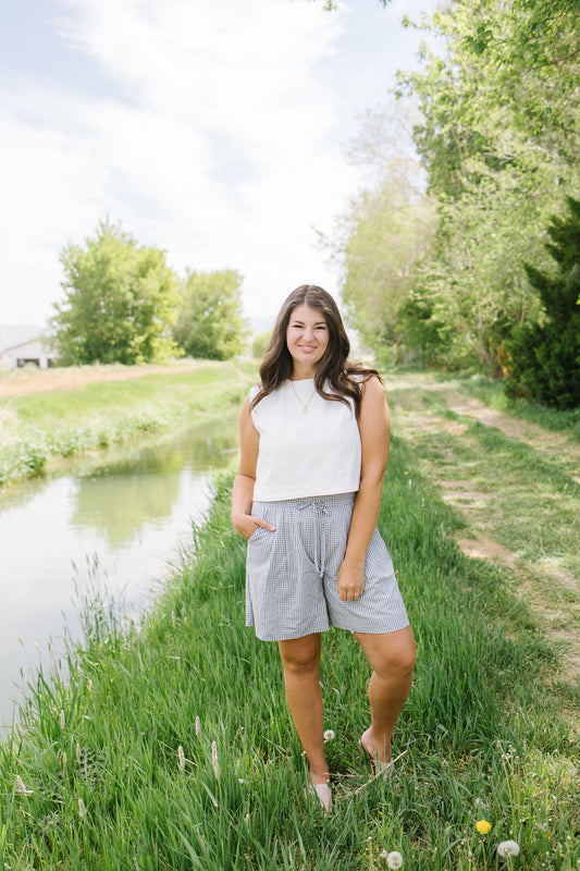 Woman standing by a pond with greenery in the background