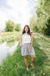 Woman standing by a pond with greenery in the background