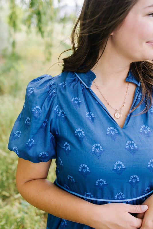 Woman wearing a blue dress with floral patterns outdoors