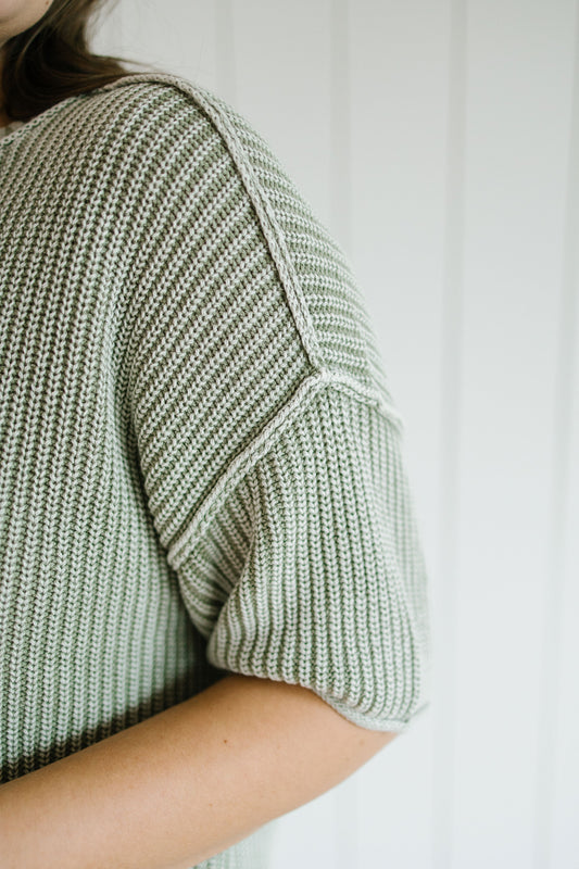 Close-up of a person wearing a green knitted sweater against a white background