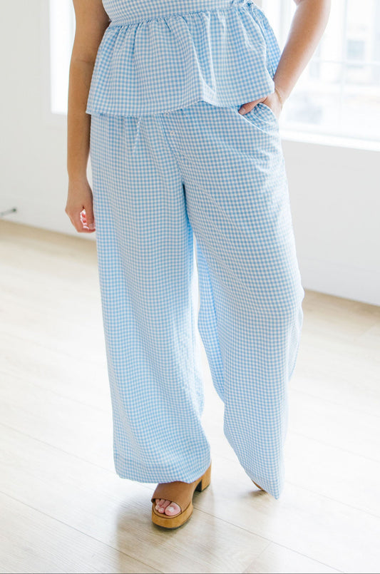 Woman wearing a blue gingham set in a bright room.