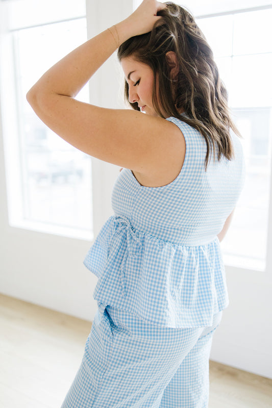 Woman wearing a light blue checkered outfit in a bright room.