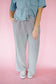 Person wearing a denim shirt and striped pants on a pink background