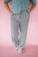 Person wearing a denim shirt and striped pants on a pink background