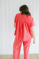 Person wearing a red lounge set standing against a white wooden panel background