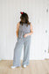 Person wearing a checkered jumpsuit standing against a white wall.