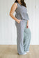 Woman wearing a checkered jumpsuit standing against a white paneled wall.
