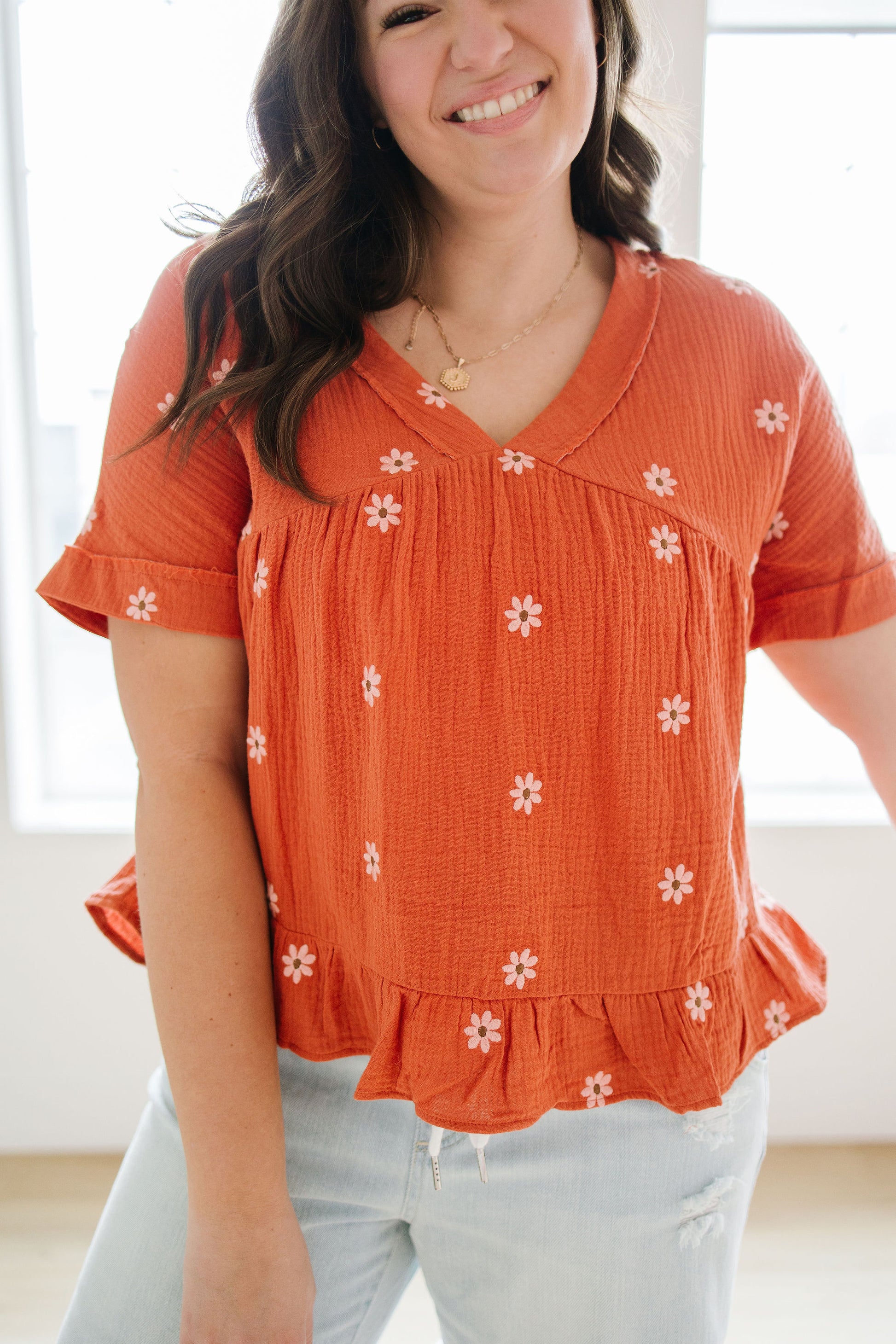 Woman wearing an orange blouse with white floral patterns indoors