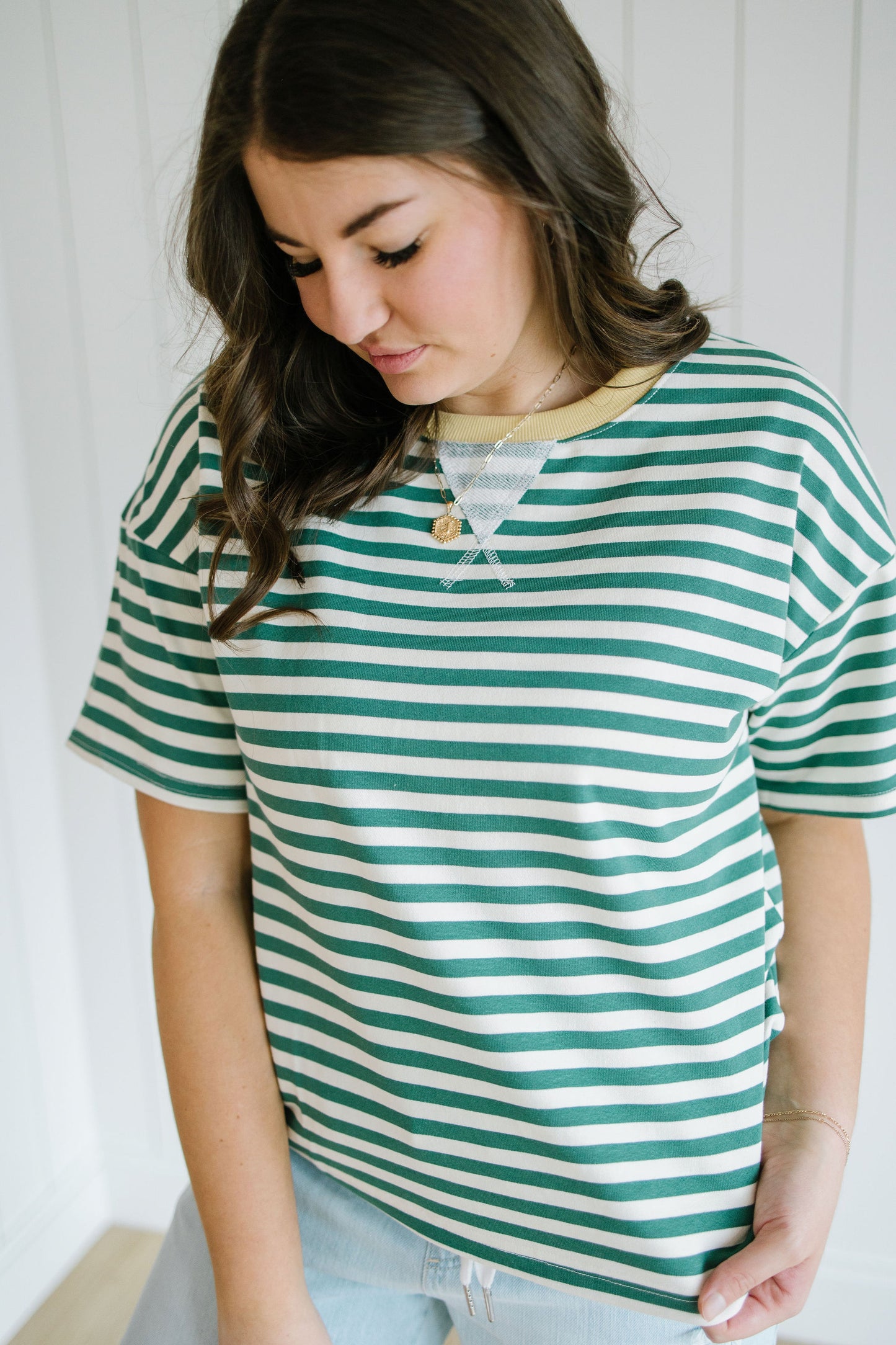 Woman wearing a green and white striped shirt against a white background