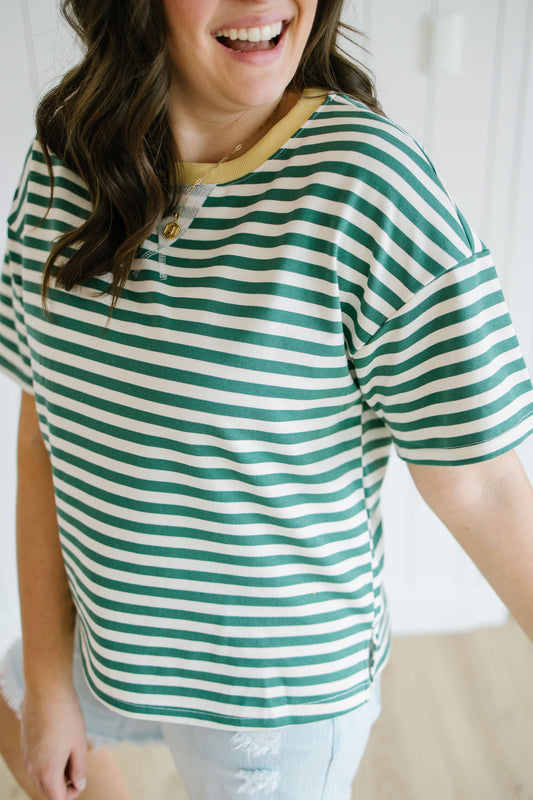 Person wearing a green and white striped shirt with a blurred background