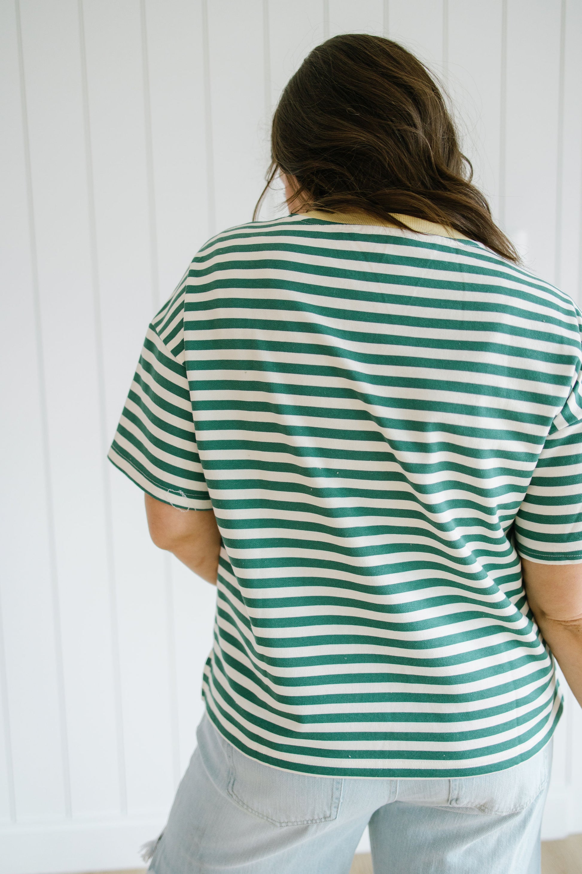 Person wearing a green and white striped shirt against a white background